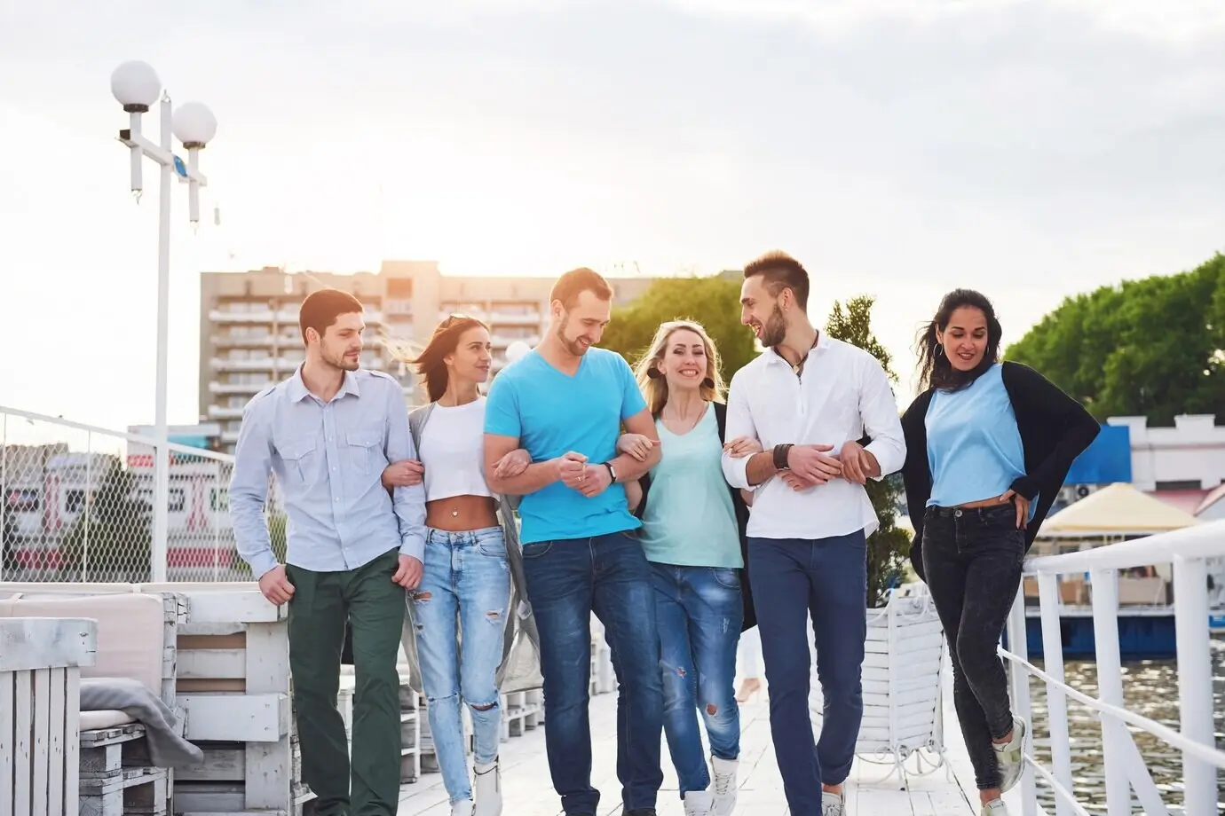 Eine lächelnde, fröhliche Freundesgruppe posiert im Freien auf dem Pier am Strand.